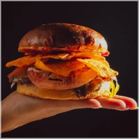 Dubbel beef patty's, rijkelijk belegd met cheddar, huisgemaakte spicy ketchup, rode ui, Dorito's en afgetopt met jalapeños. 